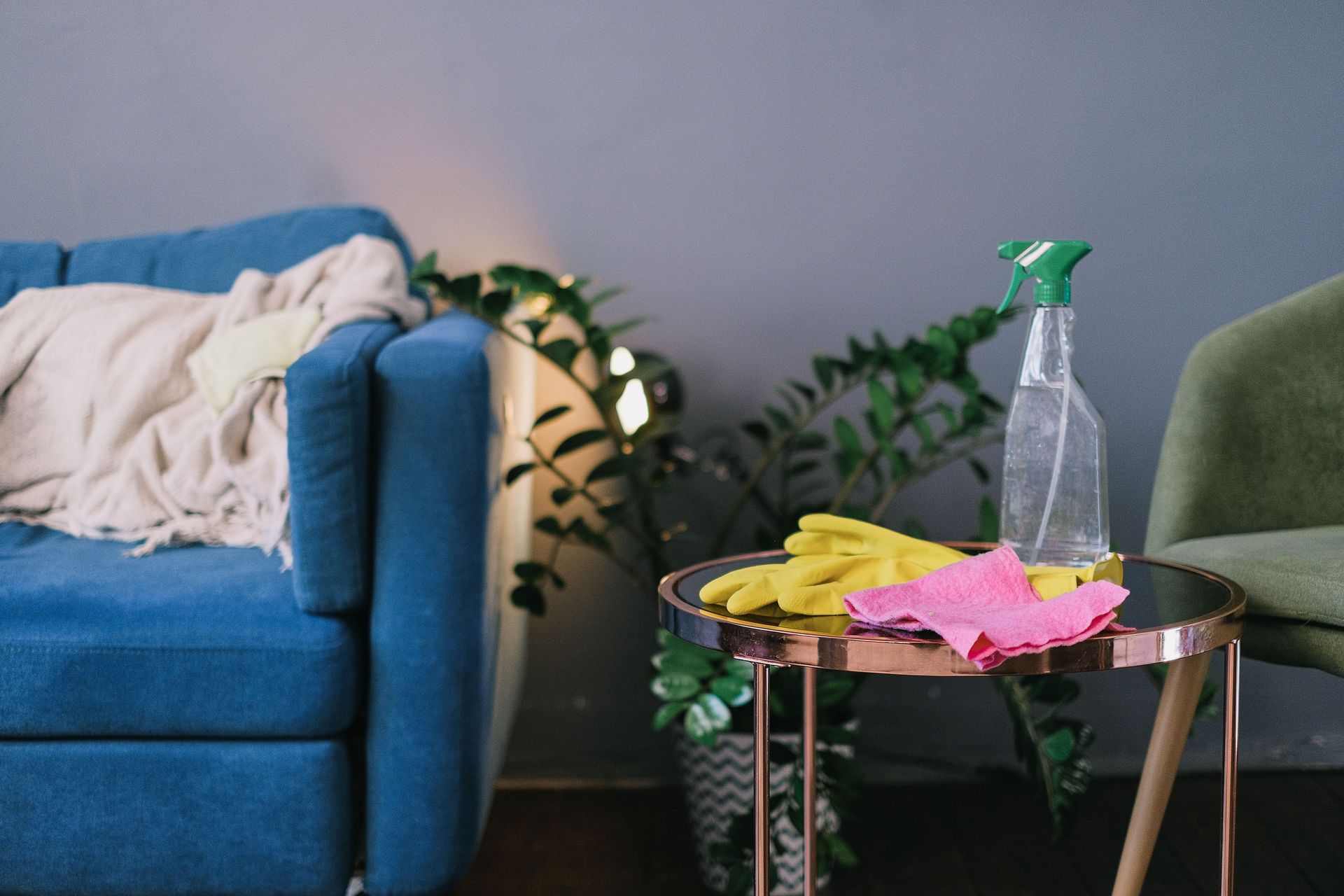 Latex gloves and spray detergent placed on table in stylish living room in daytime