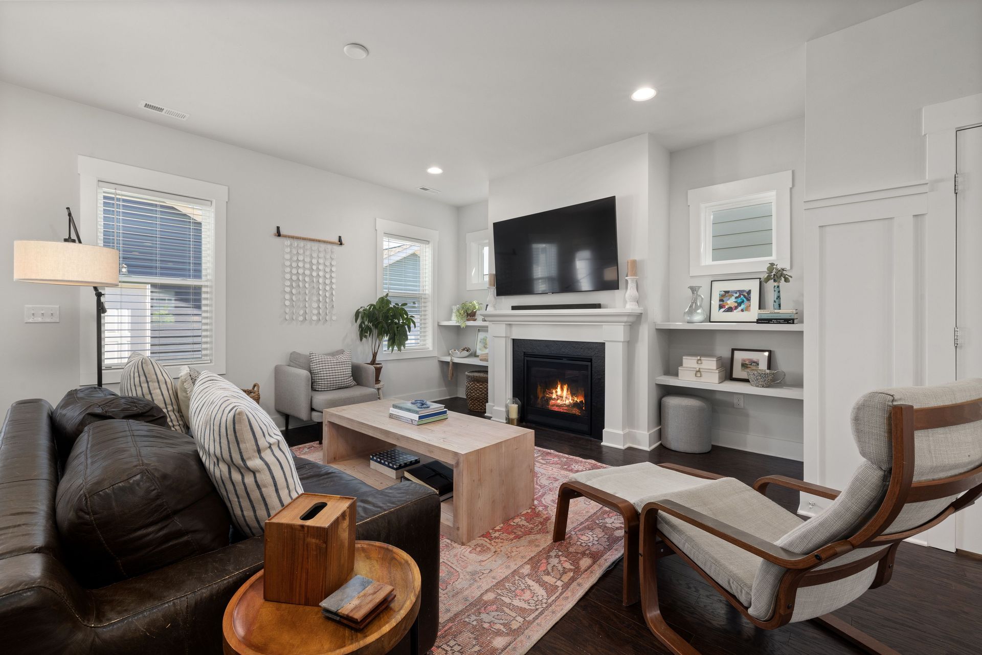 Inviting modern living room featuring a leather sofa, armchair, and a warm fireplace for relaxation.